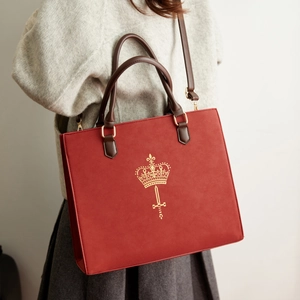 Model wearing dark red suede tote bag with golden crown logo and vintage school style