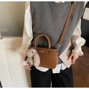 Brown suede bucket bag detail with adjustable strap and cute plush rabbit charm