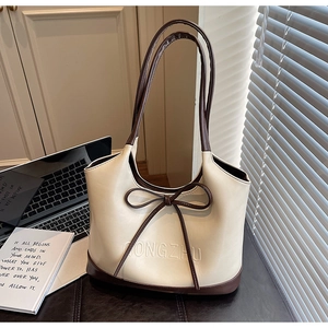 Detail of a chic cream tote bag with brown contrast trim and bow accent on an office desk