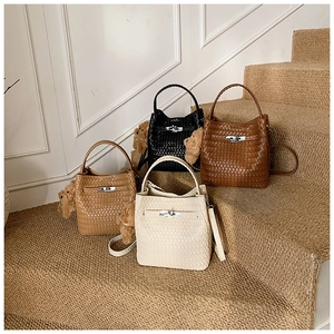 Detail showing woven texture and metal lock on four colored bucket bags on stairs