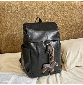 Detail of black vintage faux leather backpack featuring metal zipper and cute horse charm
