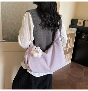 Detailed side view of a purple crescent crossbody bag with a plush rabbit charm