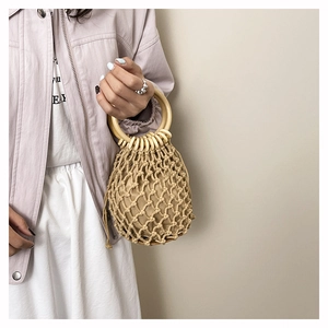 Detail of beige woven bucket bag with large wooden handles and bohemian mesh design