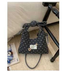 Detail of gray polka dot wool handbag with bow handle and cartoon puppy patch