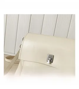 Detail shot of a beige leather crossbody bag featuring a silver rectangular hardware lock