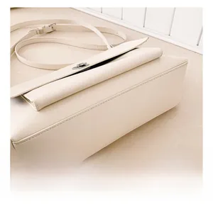 Detailed view of precision stitching and silver clasp on a cream crossbody bag