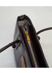 Detalle de cremallera dorada y forro gris espigado en bolso tote marrón oscuro