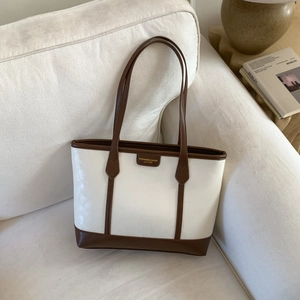 Détail du sac cabas blanc avec finitions en cuir marron et écusson avec logo doré gravé