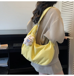 Detail of yellow hobo shoulder bag with a cute plush bear charm on nylon fabric