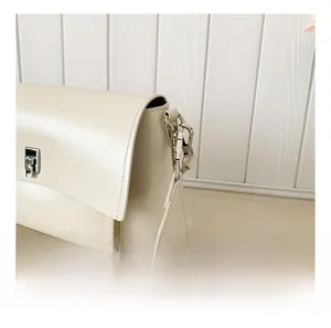 Detail showing silver metal hook and sleek clasp on a cream leather crossbody bag