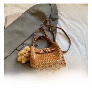 Detail of brown woven leather bucket bag with metal clasp and plush puppy charm
