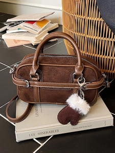Retro dark brown suede bowling bag with leather trim on vintage books background