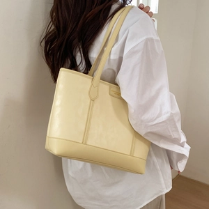 Vue détaillée du cabas en cuir jaune clair avec logo de mode embossé sur le sac