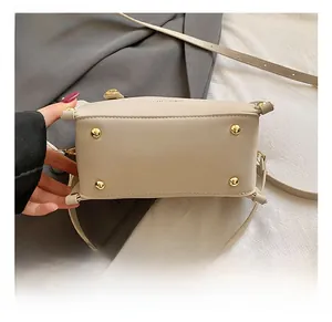Detailed bottom view of beige leather handbag with gold protective studs and fine stitching