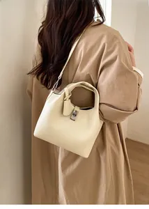 Close-up of cream-colored bucket bag with silver rotating lock and elegant leather charm