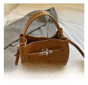 Close-up of brown woven leather bucket bag with silver metal clasp and fine texture