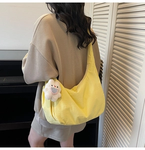 Detail of yellow crescent shoulder bag with a cute plush bunny charm worn by a model