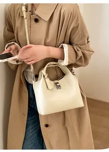 Close-up of beige lychee grain leather bucket bag with silver square lock and handle