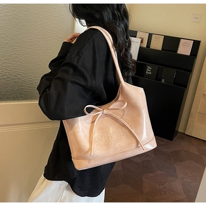 Detail showing the ribbon bow and GONGZHI embossed logo on a pink shoulder bag