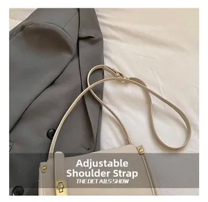 Detail of adjustable leather strap and golden metal buckle on beige crossbody bag
