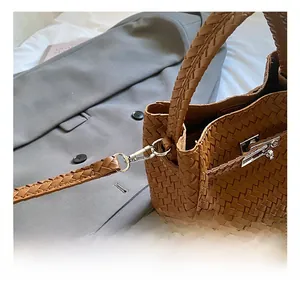 Close-up of the silver metal hook and woven leather strap on a brown bucket bag