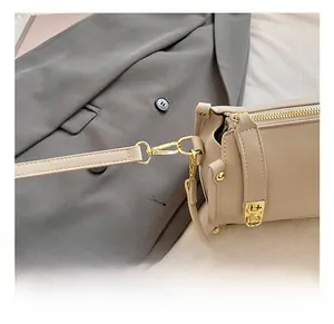 Close-up of premium gold-toned metal hook and beige leather strap on crossbody bag