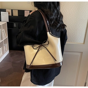 Close-up of contrast tote bag featuring elegant bow tie and brand embossing detail