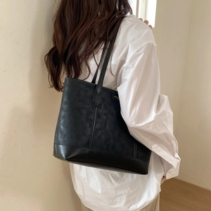 Détail d'un grand sac cabas noir minimaliste avec coutures verticales et logo doré