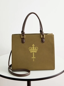 Olive green suede tote bag with golden sword and crown totem on white table