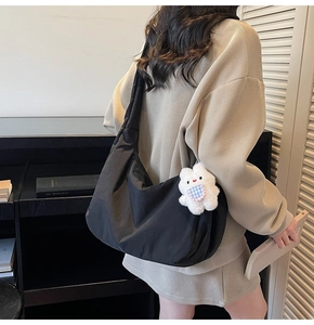 Detail of black soft dumpling crossbody bag with a cute white plush bunny charm