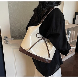 Gros plan d'un sac à main crème et marron avec finition brillante et petit nœud