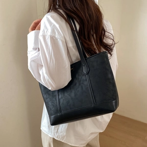 Vue détaillée de la texture en cuir noir et du logo en métal doré du sac cabas