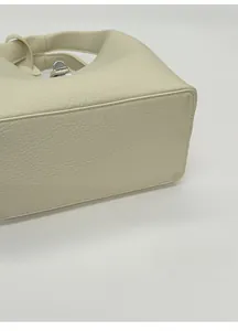 Detailed close-up of the reinforced widened base on this creamy litchi grain bucket bag