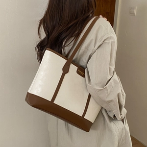 Vue détaillée d'un grand sac cabas en cuir blanc et marron porté par un mannequin