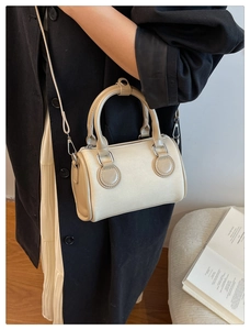 Detalle del mini bolso Boston en beige y marrón combinado con un abrigo de moda casual