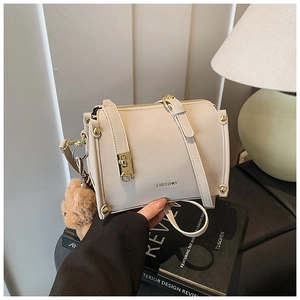 Detail der beigen Boston Tasche mit goldenen Beschlägen und süßem Bärenanhänger