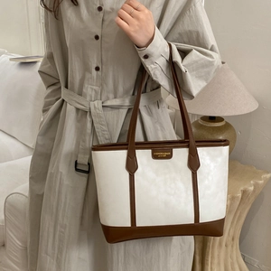 Gros plan sur le sac fourre-tout en cuir crème et marron avec logo élégant à l'avant