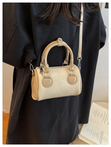 Vista trasera de una modelo con bolso Boston de lona beige y detalles en cuero caqui