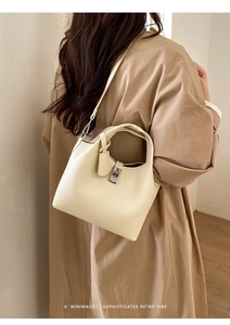 Close-up of cream-colored bucket bag in lychee pattern leather with silver hardware