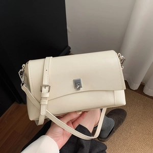 Detail of a creamy beige crossbody bag with silver metal buckle and adjustable leather strap