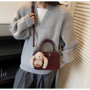 Detail of burgundy vintage crossbody bag with cute plush rabbit charm and shoulder strap