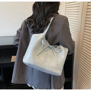 Détail du sac cabas bleu clair avec un grand nœud et lettrage de marque en relief