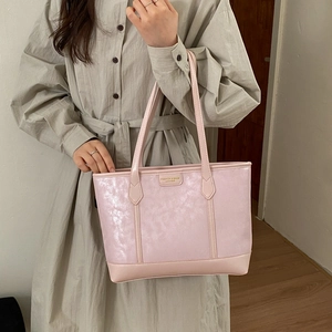Détail du sac cabas rose clair avec texture métallique nacrée et plaque signalétique dorée