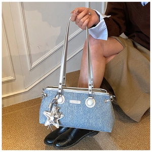 Detalle de bolso vaquero azul claro con colgante de estrella plateada y placa fashion