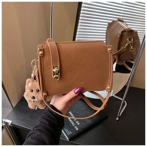 Details der braunen Retro-Tasche mit goldenem Drehverschluss und Plüsch-Hundeanhänger