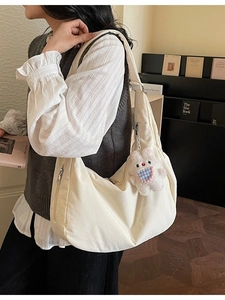 Minimalist off-white canvas dumpling bag with a cute plush bunny pendant on a shoulder strap