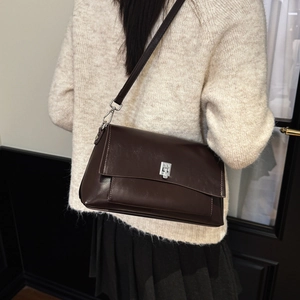 Detailed view of brown patent leather crossbody bag with silver square metallic buckle lock