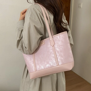 Détail du sac cabas rose clair avec finition texturée et étiquette en métal tendance