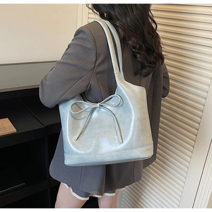 Detail of light blue faux leather tote bag with bow accent and GONGZHU embossed logo