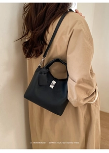Detail of black lychee grain leather handbag featuring silver clasp and top handle
